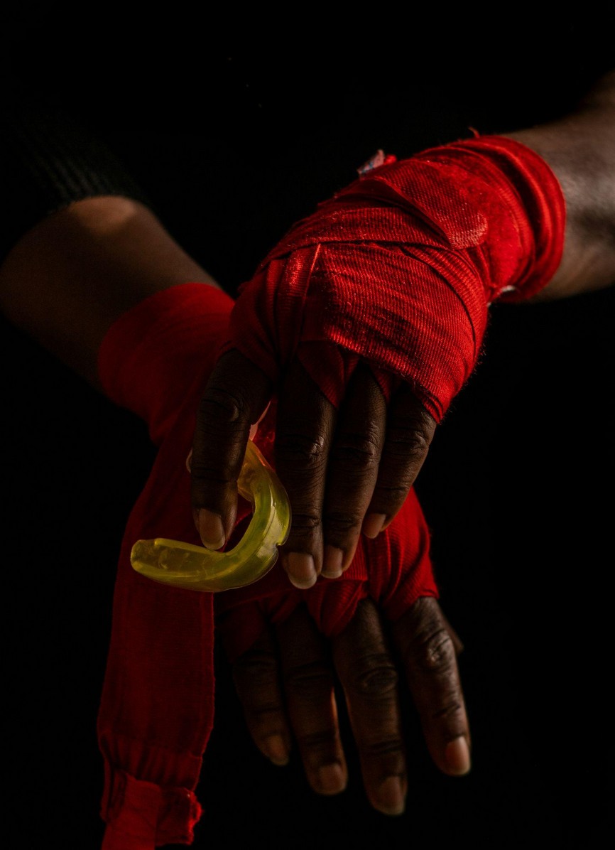 Boxer with wrapped hands holding one of the custom boxing mouthguards in Tulare before training.