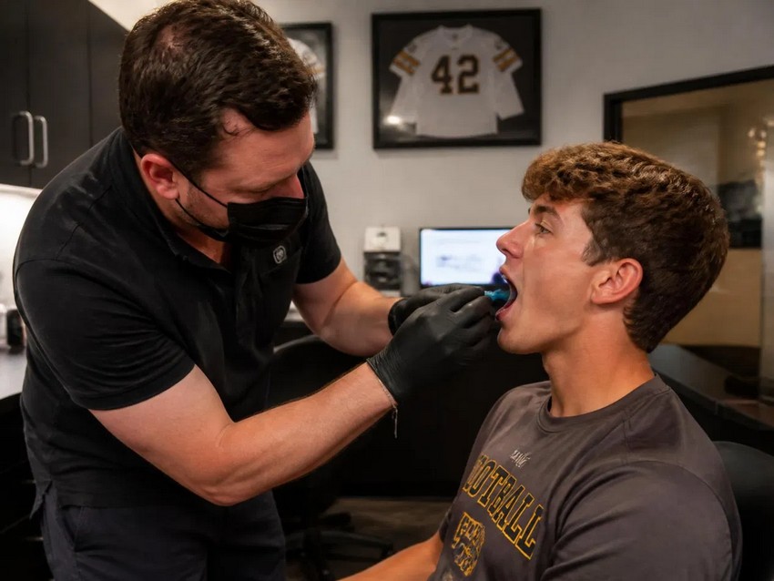 Dentist fitting custom sports mouthguards Reedley football athlete